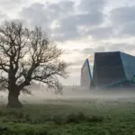 An ancient oak tree juxtaposed against a futuristic data center silhouette in a foggy meadow.